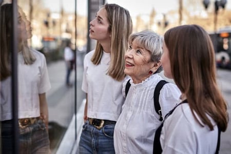 Three generations of shoppers look in a store front window at products